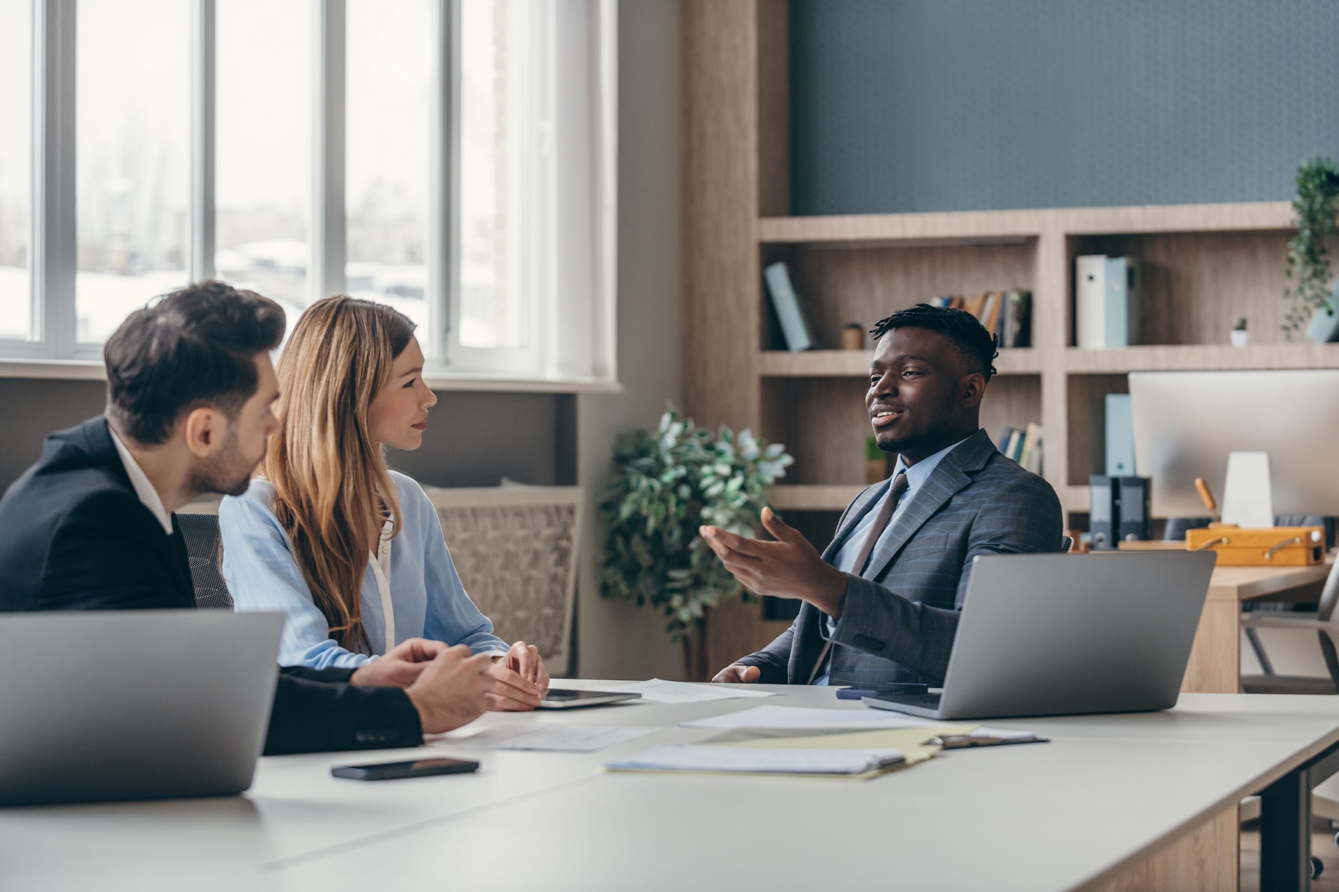 Three confident young people in formalwear discussing business during the meeting in the office